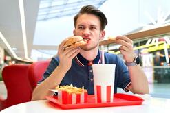 Premium Photo | Hungry crazy man is biting eating fast junk food burger, french fries and drink soda. hunger